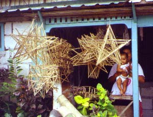 Parol skeletons hung outside, his wife and child pose beside the bamboo Mang Nonoy needs to make the parol skeletons